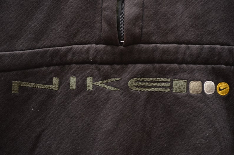 May include: A black sweatshirt with a green embroidered Nike logo and a zipper at the neck.