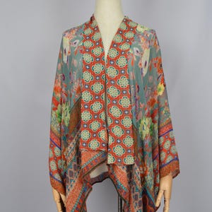 May include: A patterned kimono-style top with a V-neck. The fabric features floral and geometric designs in shades of orange, blue, and green. The garment is displayed on a mannequin.