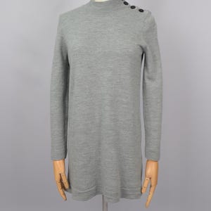 May include: A gray long-sleeved sweater with a mock neck and buttons on the shoulder.