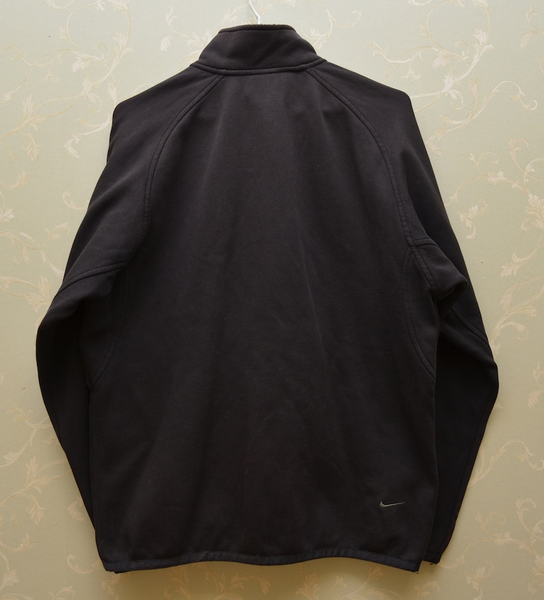 May include: A black fleece jacket with a zipper closure and a small Nike logo on the lower right side.