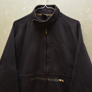 May include: A black Nike fleece jacket with a zipper and a small pocket on the left chest. The jacket has a Nike logo on the bottom left side.