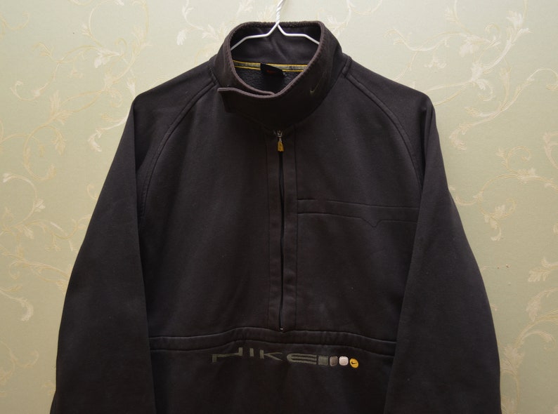 May include: A black Nike fleece jacket with a zipper and a small pocket on the left chest. The jacket has a Nike logo on the bottom left side.