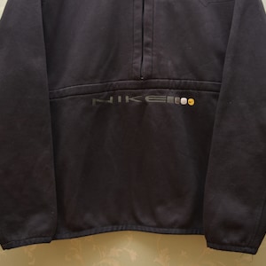 May include: A black Nike fleece pullover with a half-zip closure and the word "NIKE" embroidered in grey and yellow on the front.