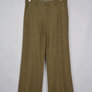 Puede incluir: Pantalón de pierna ancha de cuadros marrones y negros con cierre de botón y bolsillos.