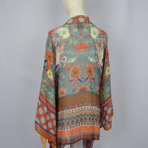 May include: A teal, orange, and red floral-print kimono. The garment has a detailed botanical pattern. The kimono is displayed on a mannequin, highlighting its design and drape. The measurements are in centimeters.