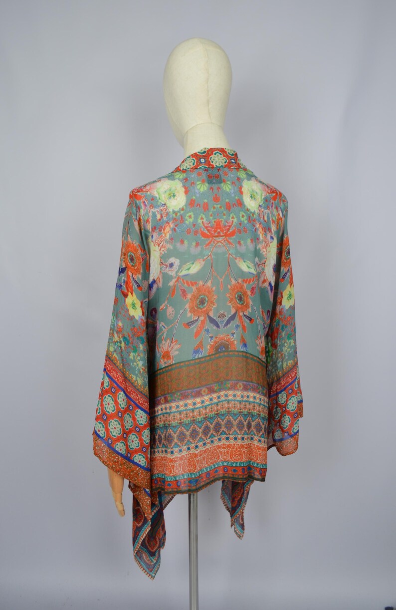 May include: A teal, orange, and red floral-print kimono. The garment has a detailed botanical pattern. The kimono is displayed on a mannequin, highlighting its design and drape. The measurements are in centimeters.