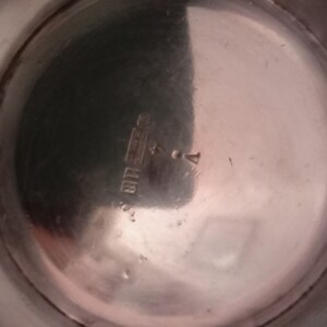 May include: Close-up of the bottom of a silver pitcher with the inscription "STERLING 925" visible.