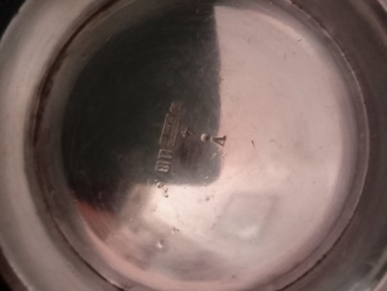 May include: Close-up of the bottom of a silver pitcher with the inscription "STERLING 925" visible.