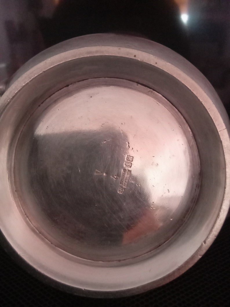 May include: The underside of a silver pitcher with the inscription "Sterling Silver, England" and the number "801" visible.