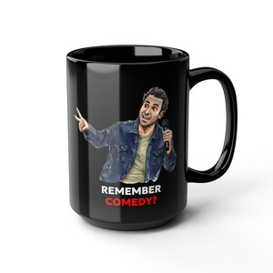 May include: Black ceramic coffee mug with a cartoon illustration of a man holding a microphone and the text "Remember Comedy?" in white letters.