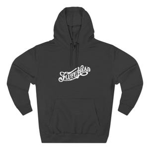 May include: Dark gray hoodie with a front pocket and a drawstring hood. The hoodie features the white text "FLUFF HEAD" in a cursive font across the chest. A casual, comfortable garment.