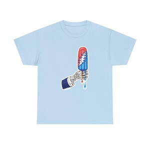May include: A light blue t-shirt featuring a graphic print of a skeletal hand wearing a dark blue suit sleeve, holding a melting red, white, and blue popsicle with a jagged white lightning bolt design running vertically down the center.