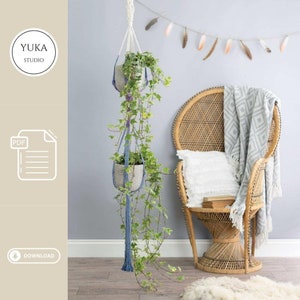 May include: A DIY macrame plant hanger with two hanging pots, featuring a blue and white color scheme. The hanger is displayed in a room with a wicker chair and a white throw blanket.
