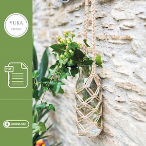 May include: A DIY macrame plant hanger made with natural twine, holding a glass bottle with green foliage and small white flowers. The hanger is attached to a stone wall. The image includes the text "YUKA STUDIO" and "PDF DOWNLOAD".