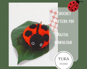 Puede incluir: Patrón de crochet PDF de descarga digital para un amigurumi de mariquita. La mariquita es roja con manchas negras y está sentada en una hoja verde. El texto "CROCHET PATTERN PDF DIGITAL DOWNLOAD YUKA STUDIO" es visible en la imagen.
