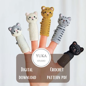 Op de afbeelding: Vijf handgemaakte gehaakte vingerpoppetjes in de vorm van katten in verschillende kleuren: grijs, wit, geel en zwart. Elke pop heeft een kattengezicht met geborduurde details. De afbeelding bevat de tekst "Yuka Studio" en "Digital Download Crochet Pattern PDF."