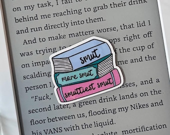 May include: A sticker of a stack of books with the words "smut", "more smut", and "smuttiest smut" on them. The sticker is placed on a Kindle e-reader with the text "attempting to fix the lid that's not pressed down completely. Of course, thanks to my attention being focused on my task, I fail to notice the person behind me reaching to grab their drink and run directly into them. And to make matters worse, that lid I was trying to... ops right off the cup of... me and the... "Fuck," ... second later, a green drink lands on the floor between us, flooding my Nikes and his VANS with the liquid. Disbelief and absolute mortification"