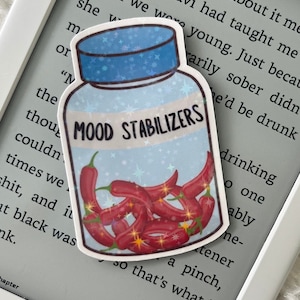 Puede incluir: Una pegatina de un frasco de píldoras azul y blanco con una etiqueta blanca que dice "MOOD STABILIZERS". El frasco está lleno de chiles rojos. El fondo es un patrón de estrellas azul y blanco.