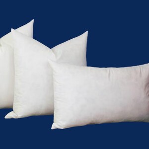 Könnte beinhalten: Drei weiße Kissenbezüge in verschiedenen Größen. Die Kissen sind aus einem weichen, flauschigen Material gefertigt und perfekt, um Ihrem Bett oder Sofa Komfort und Unterstützung zu verleihen.