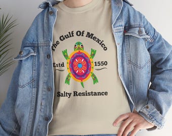 May include: A beige t-shirt with a colorful turtle graphic and the text "The Gulf of Mexico Estd 1550 Salty Resistance".