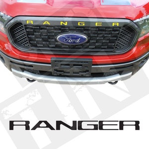 Peut inclure: Un camion Ford Ranger rouge avec une calandre noire et un lettrage "RANGER" jaune à l'avant. Le logo Ford est bleu et blanc.
