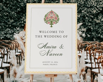 May include: A white wedding welcome sign with a gold border and a floral design. The sign reads "Welcome to the Wedding of Amira & Naveen August 12, 2024 Paris, France".