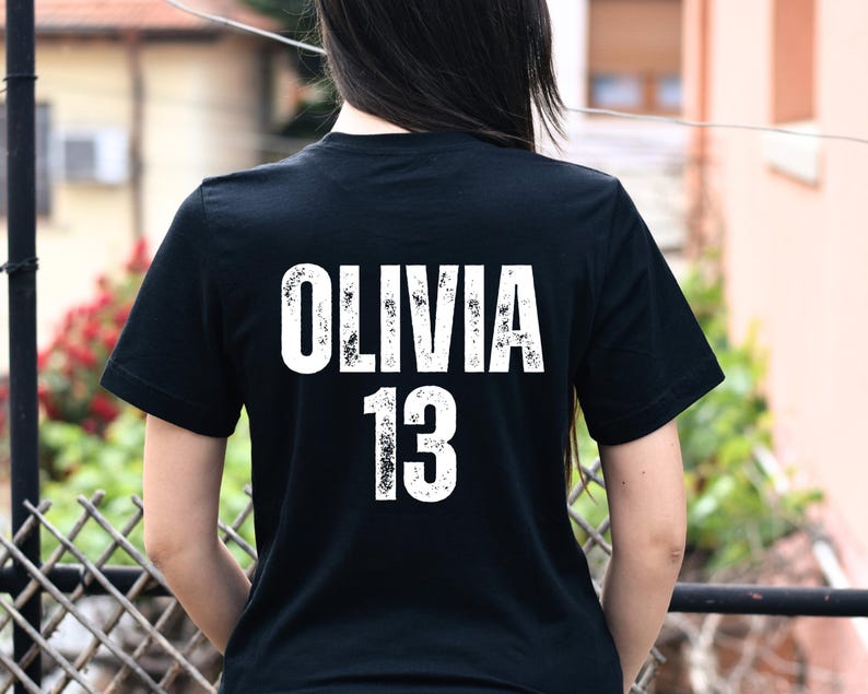 May include: Black t-shirt with white text that says "Olivia 13" on the back.