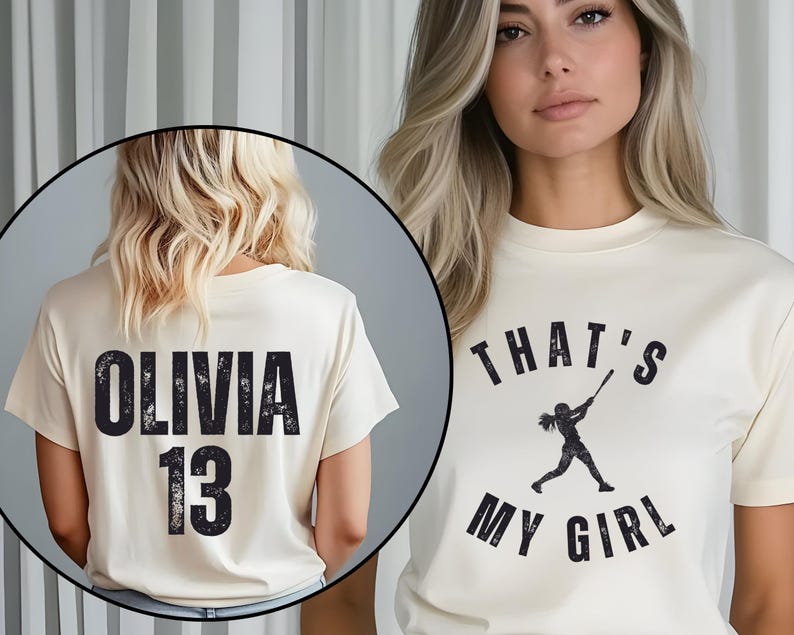 May include: Two cream colored t-shirts with black text. One shirt says "Olivia 13" and the other says "That's My Girl" with a silhouette of a girl playing baseball.
