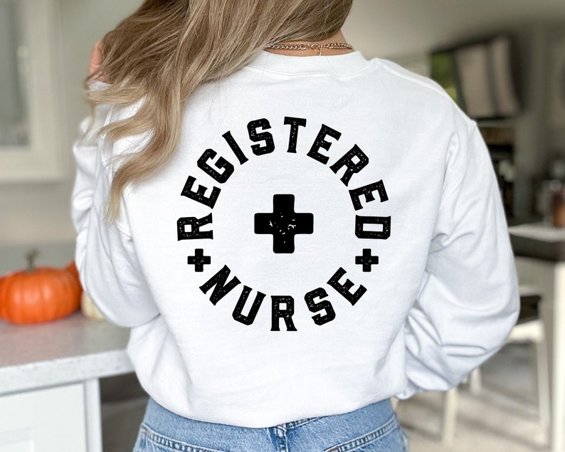 May include: White long-sleeve sweatshirt with black text that reads "Registered Nurse" in a circle with a black plus sign in the center.