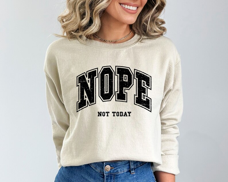 May include: A beige sweatshirt with a black graphic print that says "NOPE NOT TODAY" in a vintage collegiate style font.