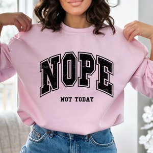 May include: Pink sweatshirt with black text that reads "NOPE NOT TODAY" in a vintage collegiate font.