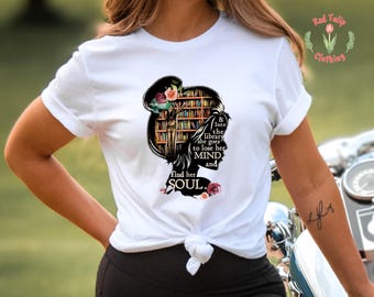 May include: White t-shirt with a graphic of a woman reading in a library. The text on the graphic reads "& into the library she goes to lose her MIND and find her SOUL."