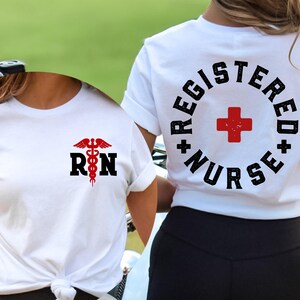 May include: Two white t-shirts with a red medical symbol and the text "RN" on the front and the text "Registered Nurse" with a red cross on the back.