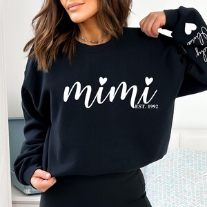 May include: Black sweatshirt with white text that reads "mimi est. 1992" with two small white hearts on either side of the word "mimi".