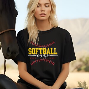 May include: Black t-shirt with a yellow and red graphic of a baseball with the text "SOFTBALL mimi" on it.