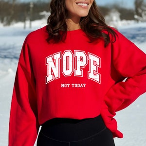 May include: Red cropped sweatshirt with white text that reads "NOPE NOT TODAY".
