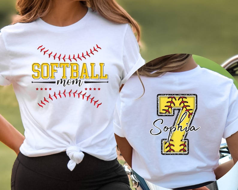 May include: Two white t-shirts with a softball theme. One shirt says "Softball Mom" with a red and white baseball stitch design. The other shirt has a large number 7 with a softball inside and the name "Sophia" underneath.