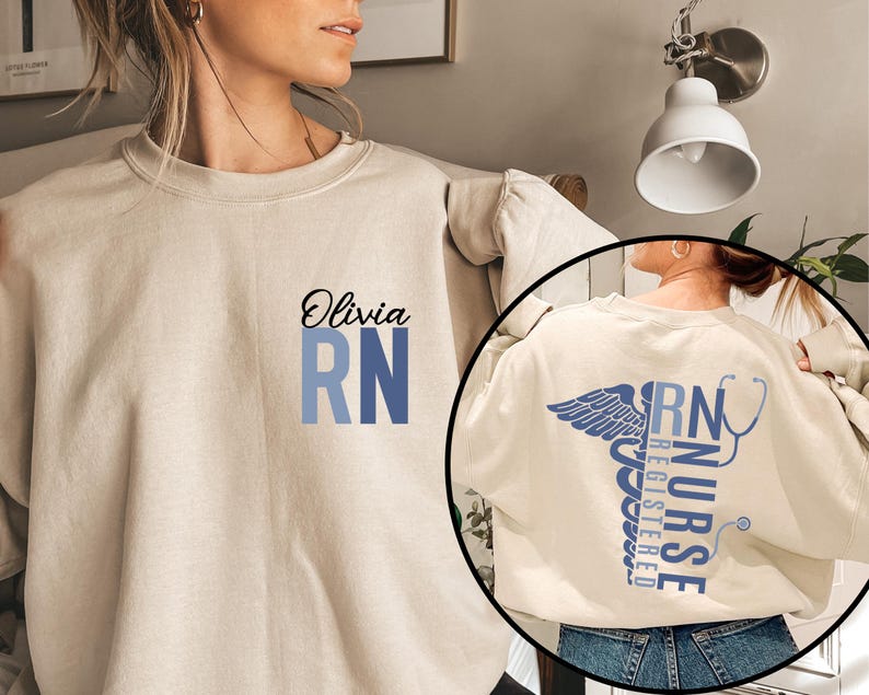 May include: A beige sweatshirt with the text "Olivia RN" printed on the front. The sweatshirt has a blue and white gradient design. The back of the sweatshirt features a stylized caduceus with the text "RN NURSE REGISTERED" printed vertically.