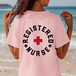 May include: Pink t-shirt with a black and white graphic that says "Registered Nurse" with a red cross in the center.
