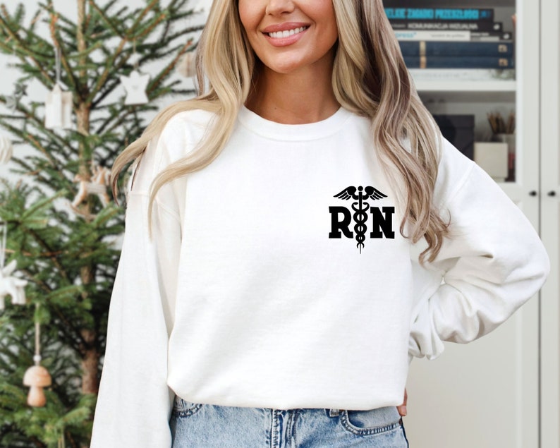 May include: White long-sleeved sweatshirt with a black graphic of a caduceus and the letters "RN".