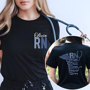 May include: Black t-shirt with the text "Olivia RN" on the front and a vertical design on the back that reads "RN NURSE REGISTERED" with a caduceus and stethoscope graphic.