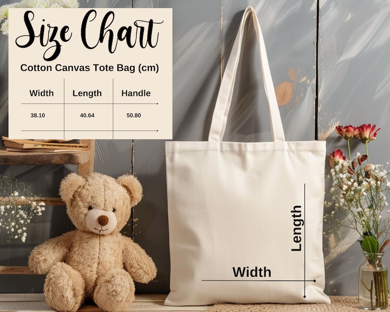 May include: A white cotton canvas tote bag with a size chart showing the width, length, and handle measurements in centimeters. The bag is shown on a gray wooden background with a teddy bear and flowers.