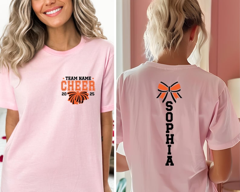 May include: A light pink t-shirt featuring a front graphic with the text TEAM NAME CHEER 2025 and a pom-pom illustration. The back of the shirt displays a large orange and black bow graphic above the vertical text SOPHIA in bold black letters.