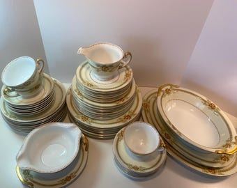 May include: A set of vintage fine china dinnerware with a floral pattern in shades of gold, brown, and white. The set includes plates, bowls, and a creamer.