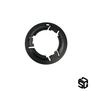 May include: Black plastic ring with five evenly spaced notches around the circumference. The ring is designed to hold a round object in place.