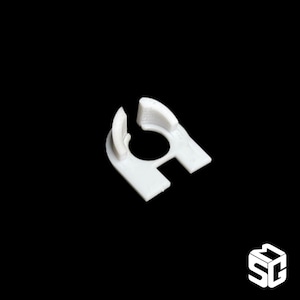 Pode incluir: Peça de plástico branco impressa em 3D com uma abertura circular e um pequeno lábio em um lado.