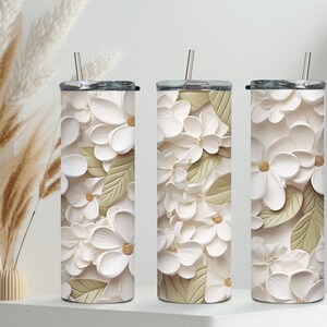 May include: Three stainless steel tumblers with white and gold floral designs. The tumblers have lids and straws.