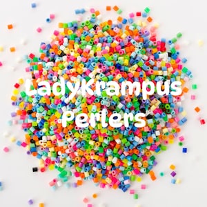 Puede incluir: Un montón de cuentas Perler de colores, incluyendo rojo, naranja, amarillo, verde, azul y morado. El texto "Ladykrampus Perlers" está superpuesto a las cuentas.