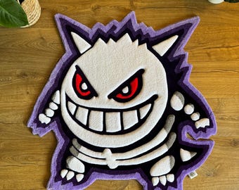 Puede incluir: Una alfombra de felpa morada y blanca con un personaje de dibujos animados con un diseño esquelético y ojos rojos. El personaje sonríe con dientes grandes.