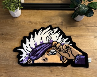 May include: A white, purple, and black rug with a cartoon character's face. The character has white hair, a purple headband, and one blue eye visible. The rug is shaped like a half-circle.